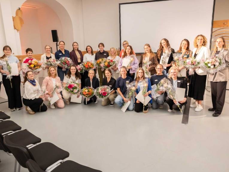 Frauen mit Blumensträußen in den Händen posieren vor der Kamera.