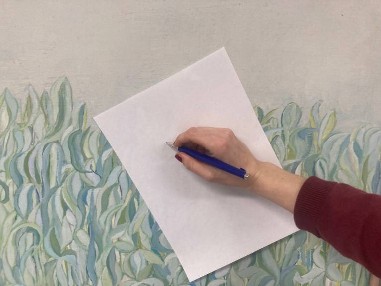 Hand mit Stift die auf ein weißes Blatt schreibt