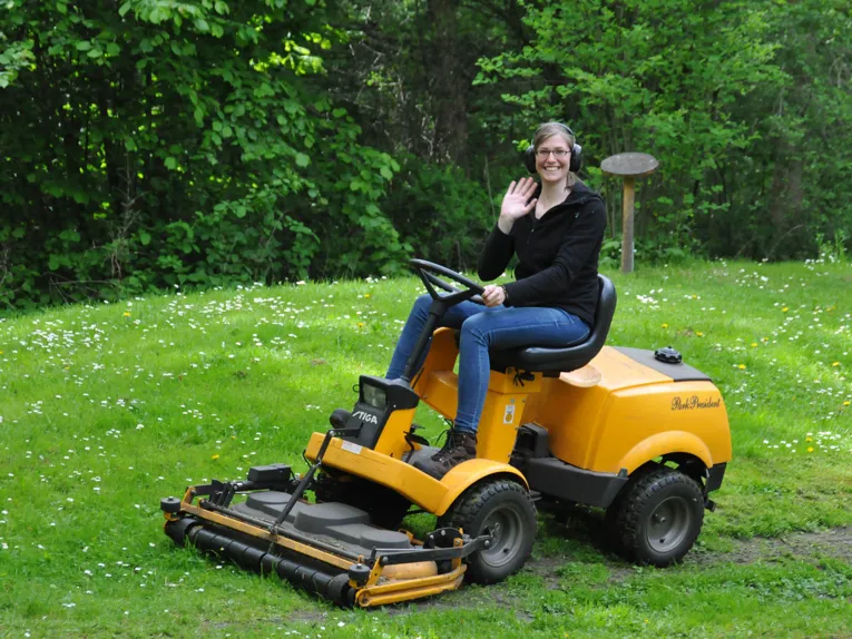 Junge Dame auf Rasentraktor sitzend