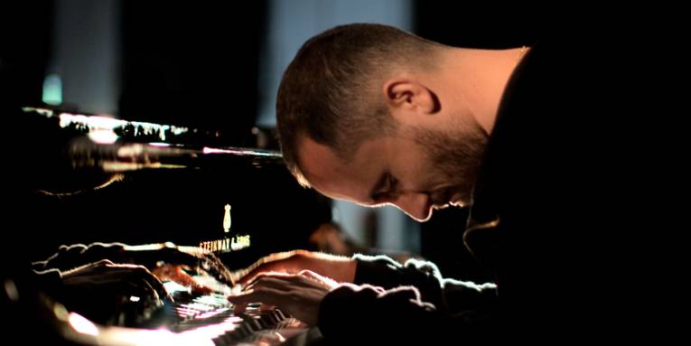 Ein Mann spielt Klavier, lehnt sich dabei mit dem Oberkörper nach vorn