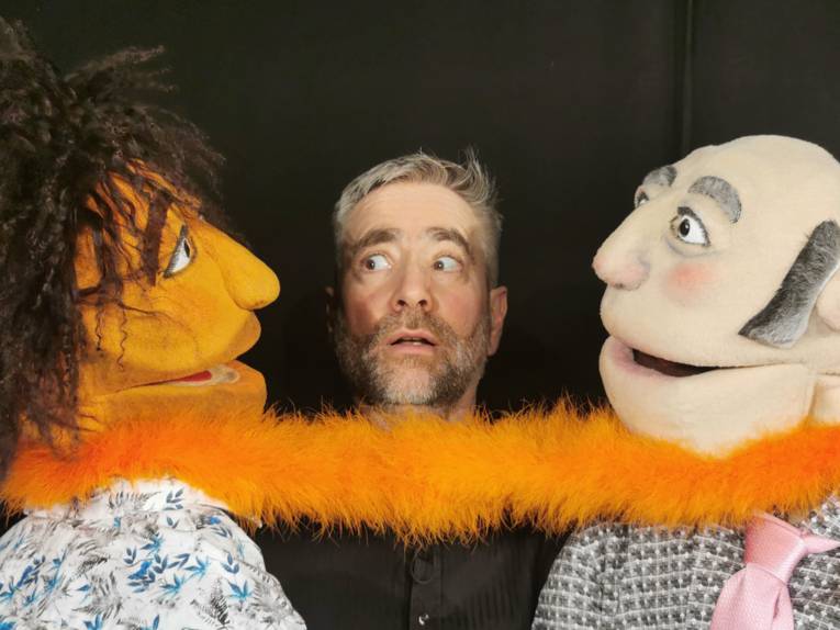 Schauspieler mit zwei mannsgroßen Puppen