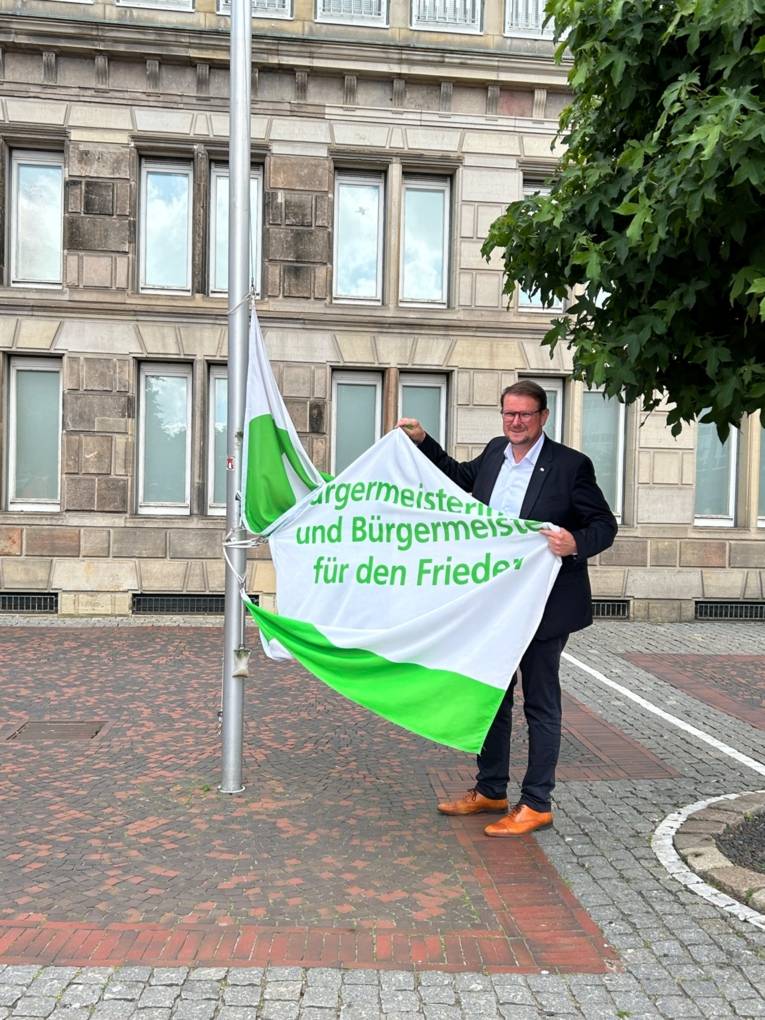 Oberbürgermeister Tim Kruithoff hisst die Flagge der mayors for Peace – sie weht dauerhaft vor dem Emder Rathaus.