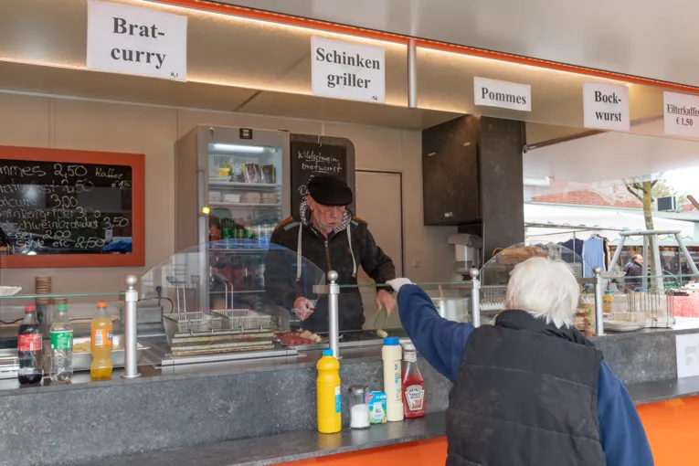 Eine Kundin kauft Bratwurst an einem Stand.