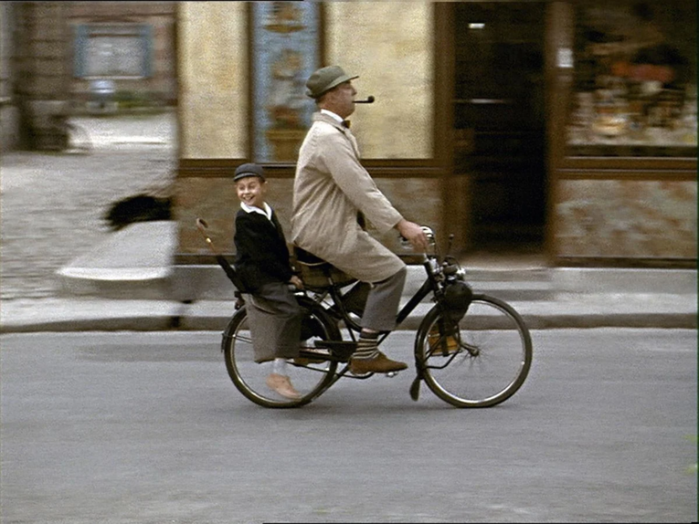 Mann fährt Fahrrad mit einem Jungen auf dem Gepäckträger.