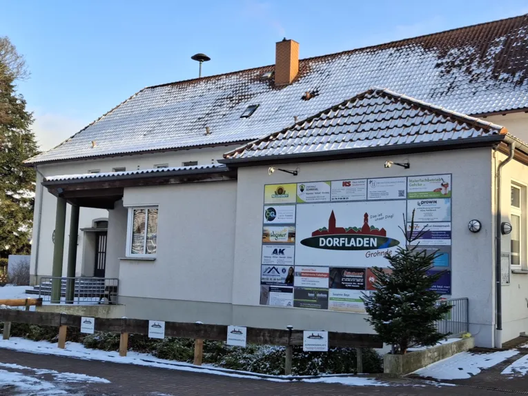 Helles Gebäude mit einem Schild Dorfladen