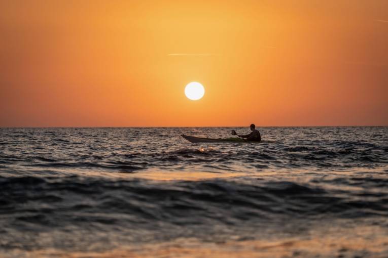 Ein Kajakfahrer fährt in den Sonnenuntergang