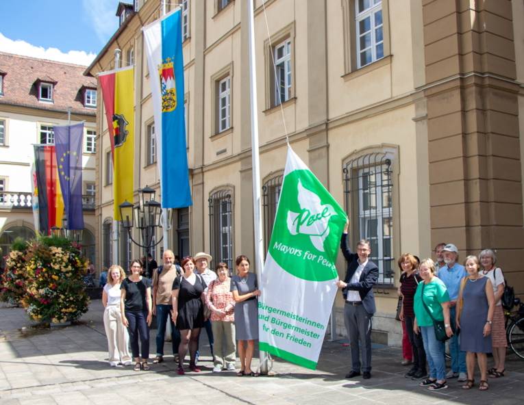 Würzburg - Oberbürgermeister Christian Schuchardt und Stadträtin Barbara Meyer hissen gemeinsam mit Mitgliedern von Friedensorganisationen die Mayors for Peace Flagge im Rathausinnenhof.