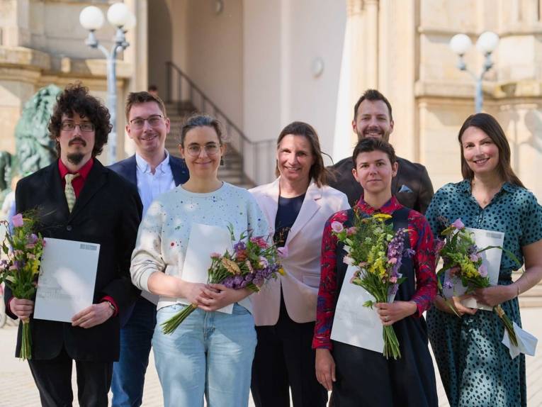 Menschen mit Urkunden und Blumensträußen