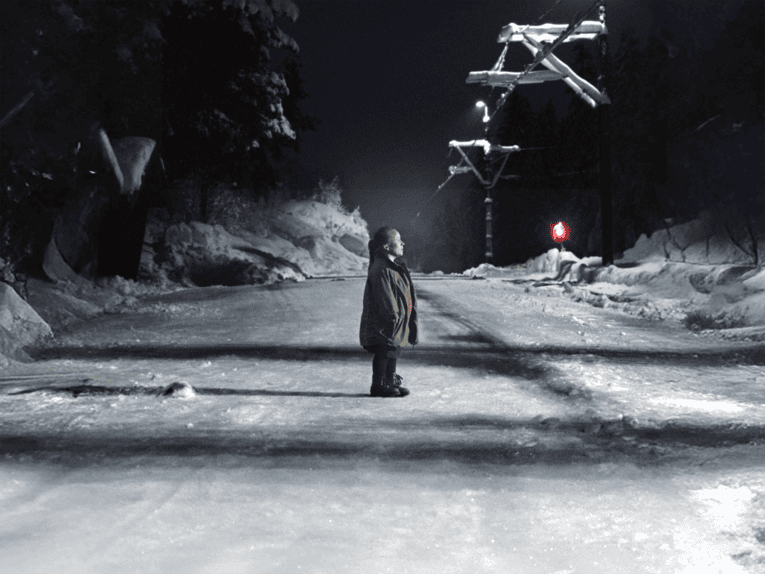 Eine weiblich gelesene Person steht allein auf einer verschneiten Straße