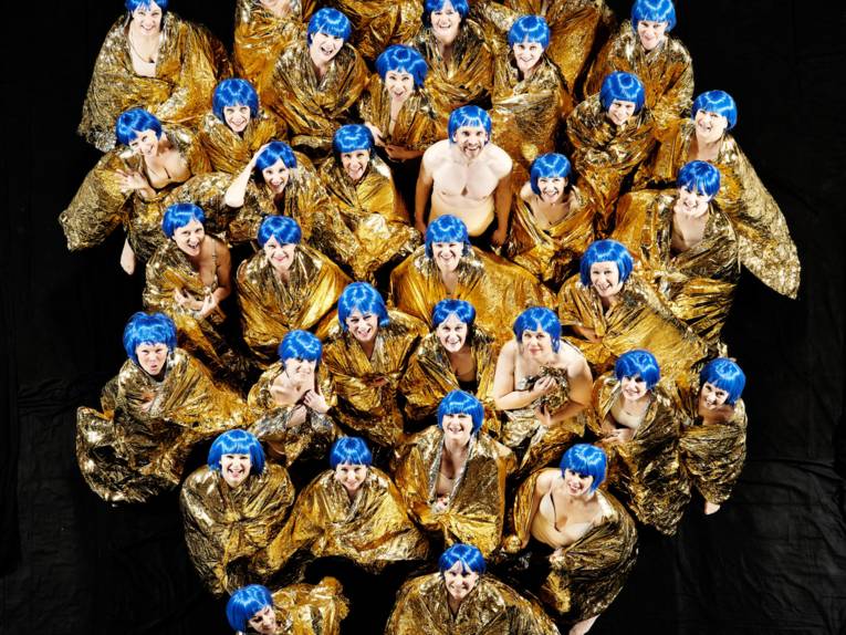 Frauenchor gekleidet in Gold mit blauen Haaren