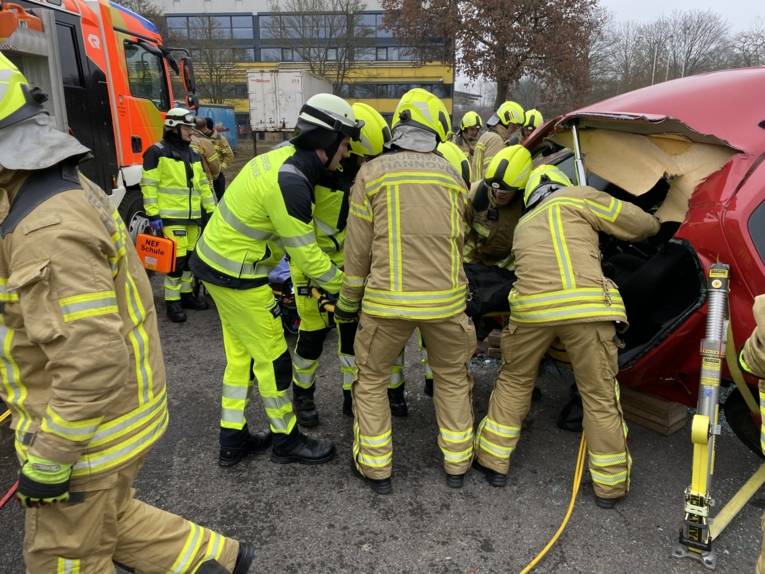 Auszubildende in der Abschlussübung, die aus einem abgestützten Auto eine Simulationspuppe retten