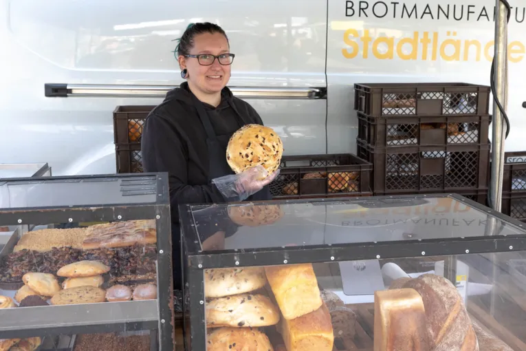 Eine Verk&auml;uferin h&auml;lt ein frisch gebackenes Brot in die Kamera.