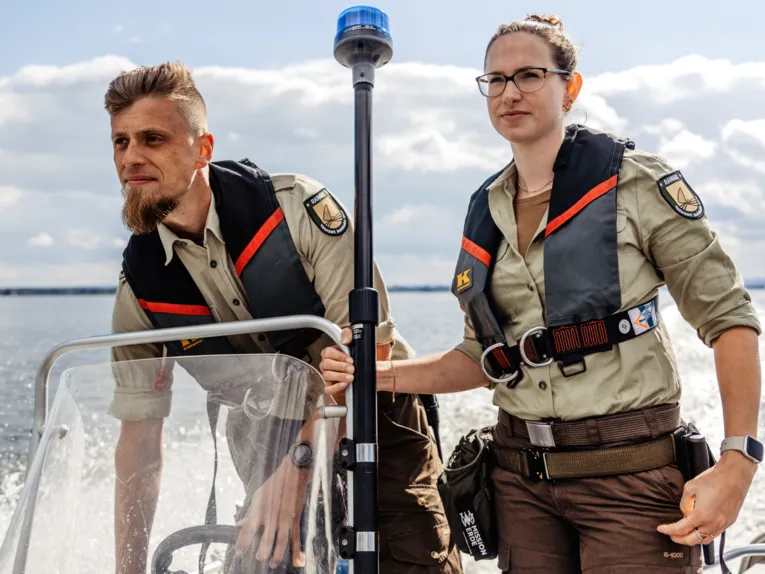 Eine Rangerin und ein Ranger fahren mit einem Boot.