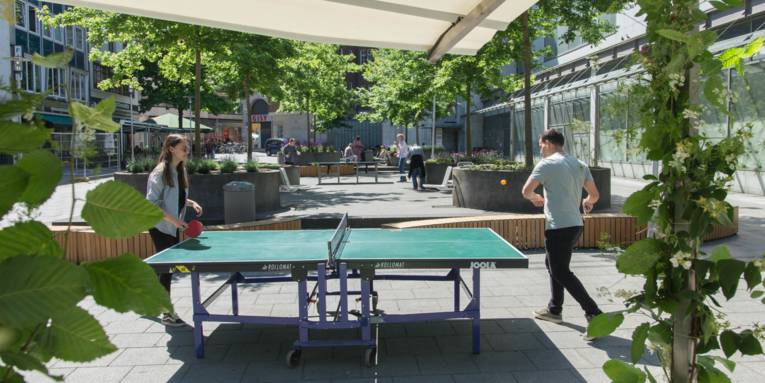 Zwei Personen an einer Tischtennisplatte in der Innenstadt.