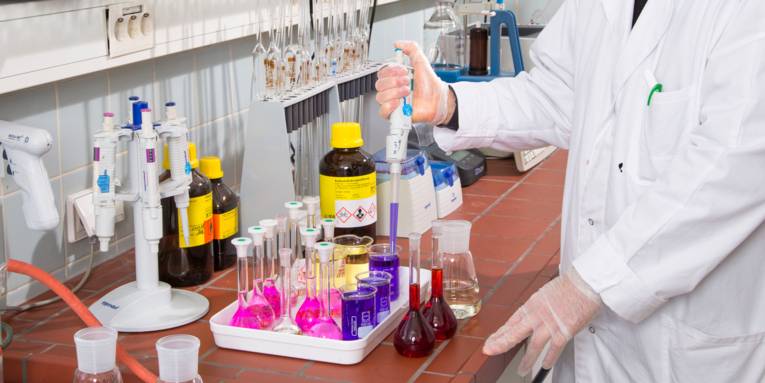 Verschiedenfarbige Flüssigkeiten, Untersuchungsgeräte und Messgefäße in einem Labor.