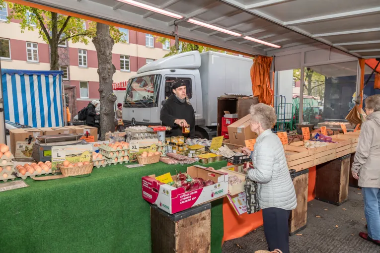 Eine Kundin kauft Eier und Honig bei einem Verk&auml;ufer auf dem Wochenmarkt.