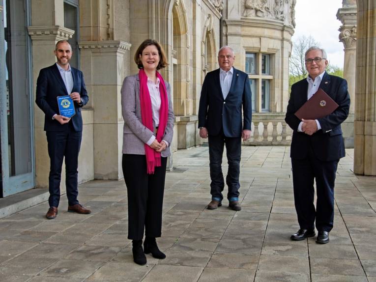Vier Personen mit Abstand auf einem Balkon.