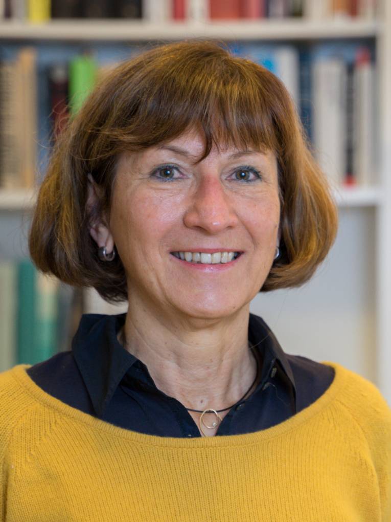 Portraitfotografie einer Frau mit einem verschwommenen Bücherregal im Hintergrund.