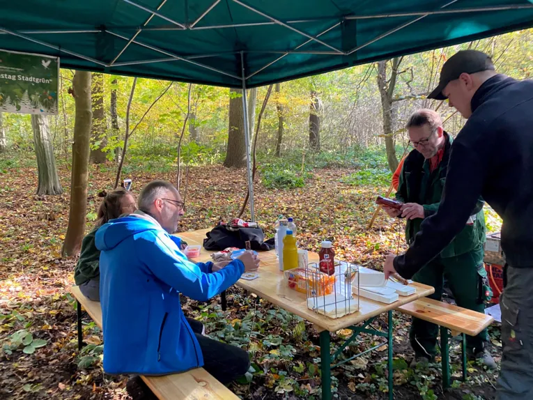 Menschen, die sich im Wald mit Gegrilltem st&auml;rken.