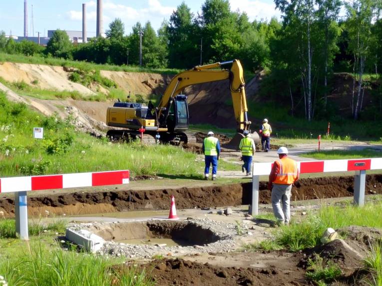 Symbolbild, das Menschen bei Sondierungsarbeiten auf einer Grünfläche zeigt.