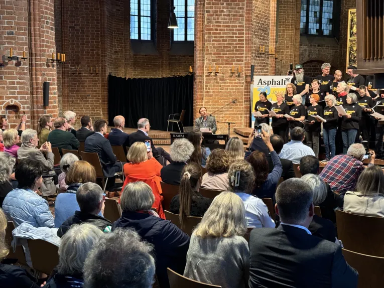 Ein Chor singt in der Marktkirche vor den gut gef&uuml;llten Besucherb&auml;nken.