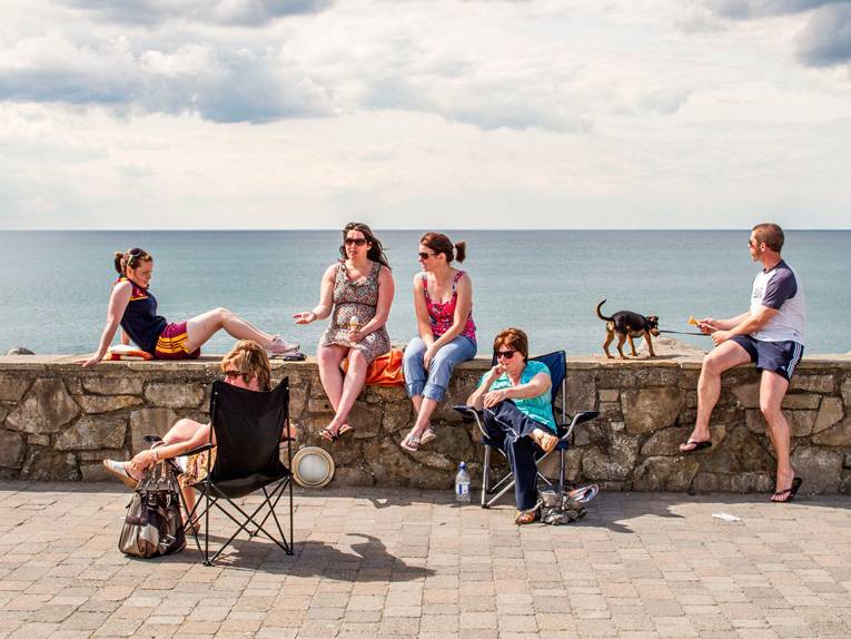 Fünf Frauen und ein Mann sitzen vor und auf einer Mauer
