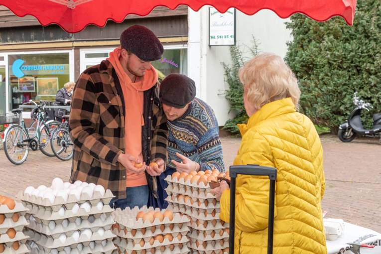 Eine Kundin auf Eier auf dem Wochenmarkt; die Händler machen eine Qualitätskontrolle