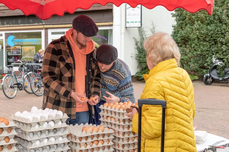 Eine Kundin auf Eier auf dem Wochenmarkt; die H&auml;ndler machen eine Qualit&auml;tskontrolle