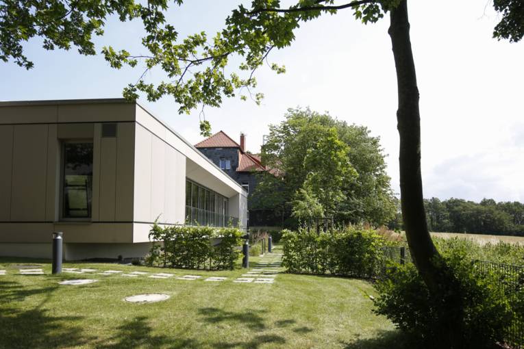 Multifunktionsgebäude im Vordergrund, im Hintergrund sieht man das Haus Humme mit grauer Schieferfassaden