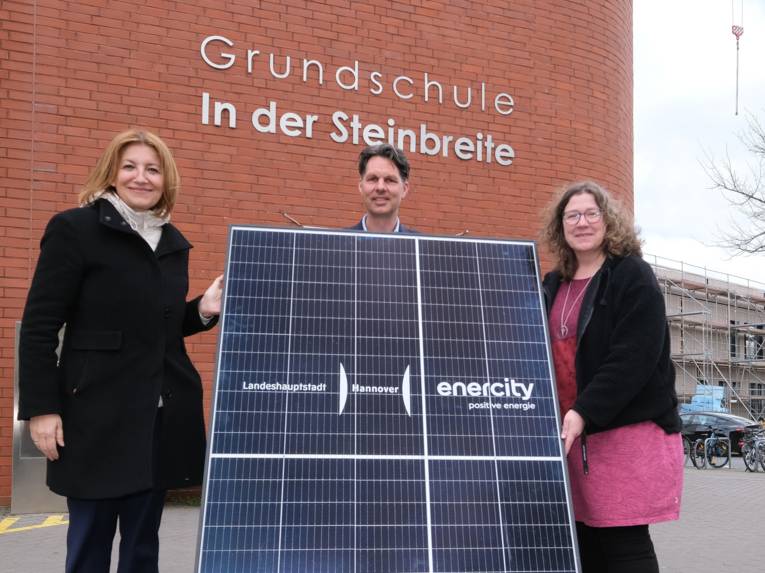 Drei Personen mit einer Photovoltaik-Anlage.