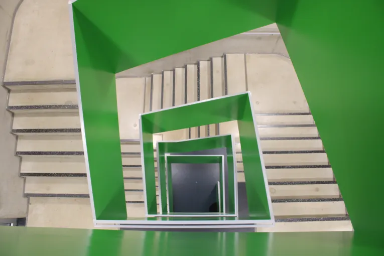 Eine eckiges Treppenhaus von oben mit Stufen und gr&uuml;nen Elementen in der Mitte.