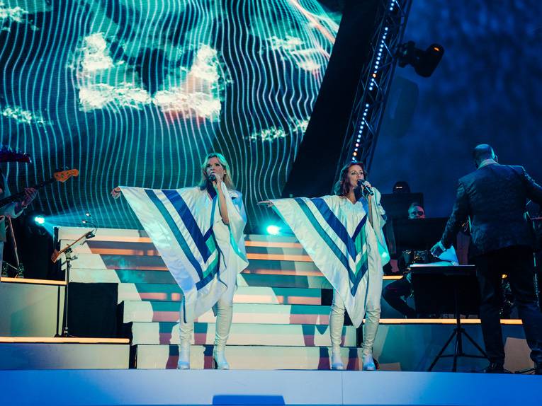 Zwei Frauen in ABBA-Kost&uuml;men stehen auf der B&uuml;hne und singen