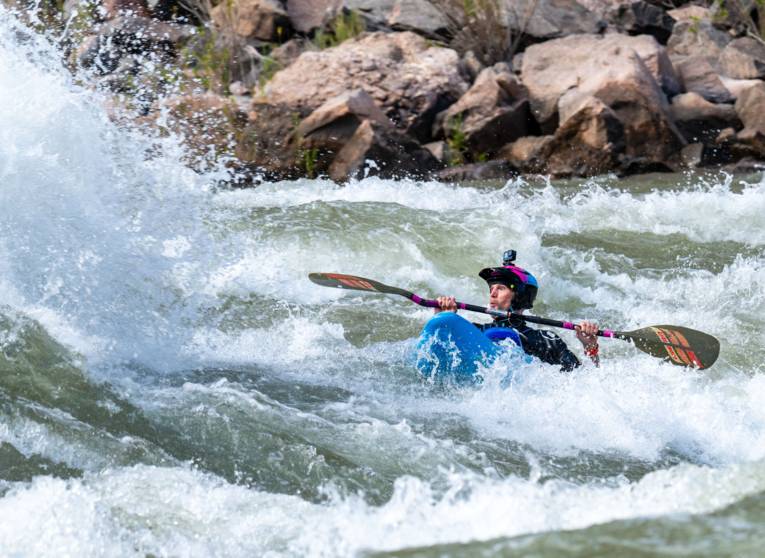 Ein Kajakfahrer fährt auf eine große Welle zu