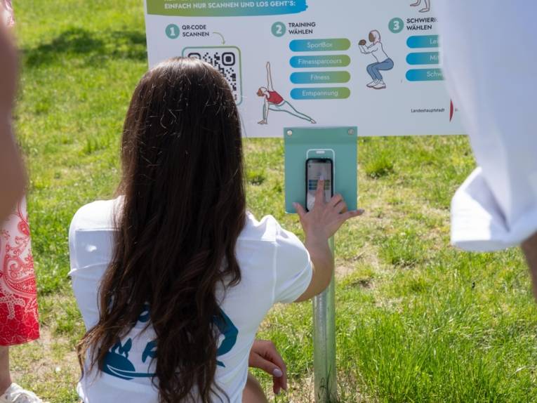 Eine Person, die im Freien einen QR-Code scannt.