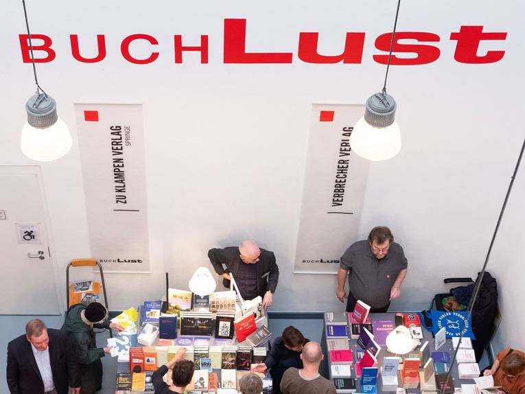 Menschen schauen sich auf einer Buchmesse an den Ständen um