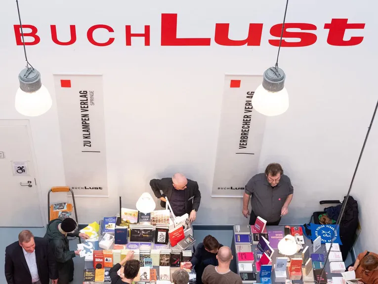 Menschen schauen sich auf einer Buchmesse an den Ständen um