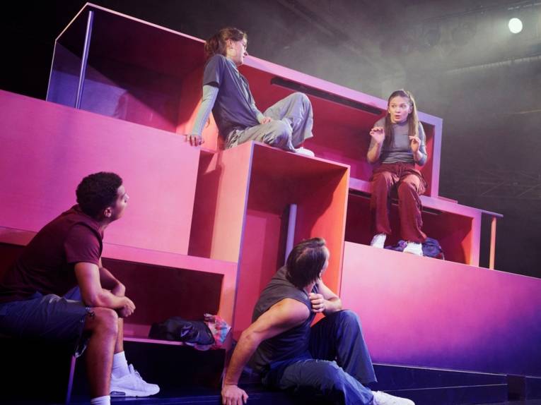 Schauspieler und Schauspielerinnen in einer Bühnekulisse aus großen Klötzen.