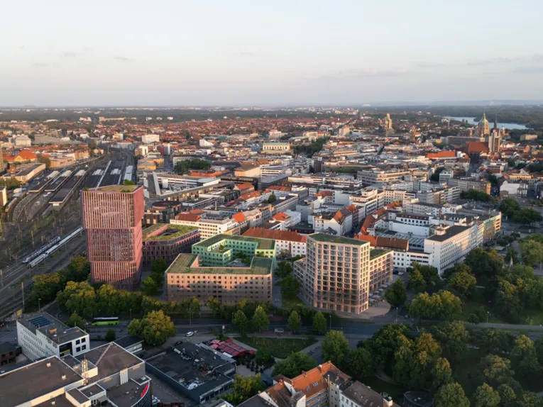 Vogelperspektive auf Geb&auml;ude, B&auml;ume, Stra&szlig;en und Wege. Bis zum Horizont eine gro&szlig;e Stadt.