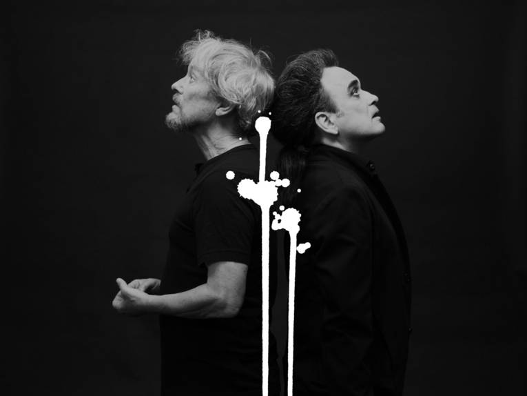 Schwarz-Weiß-Bild von zwei Männern, die Rücken an Rücken stehen.
