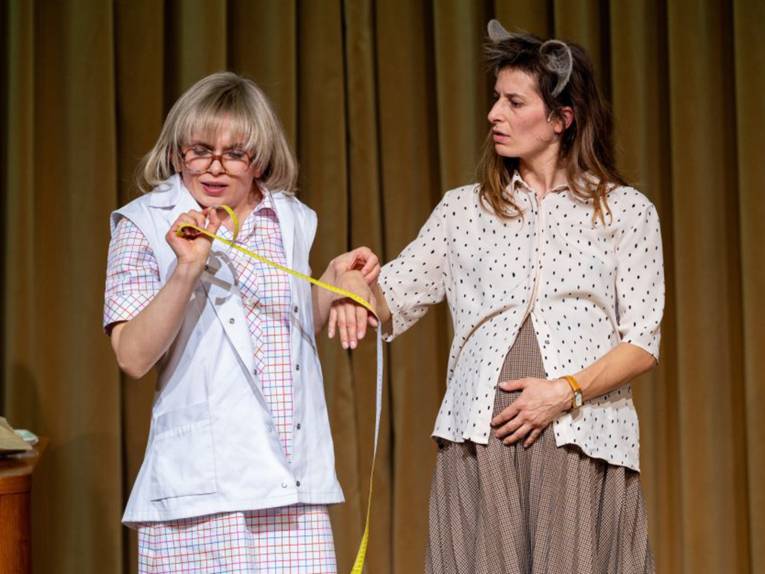 Eine Frau misst bei einer anderen schwangeren Frau den Puls.