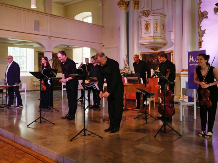 Künstlerinnen und Künstler verneigen sich nach einem Auftritt in einer Kirche vor dem Publikum.