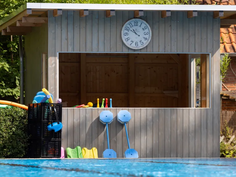 Holzh&uuml;tte, vor der Schwimmhilfen und Schwimmspielzeug liegt