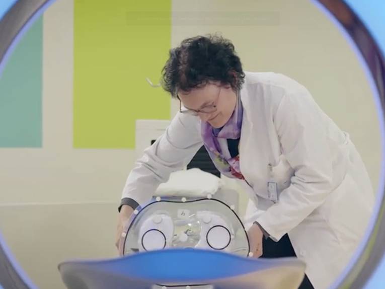 Frau in Doktorkittel an einem technischen Gerät
