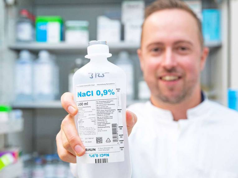 Mann hält Flasche mit der Aufschrift "NaCl 0,9%" in der Hand