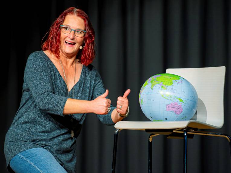 Eine Frau neben einem Stuhl auf dem ein Globus steht