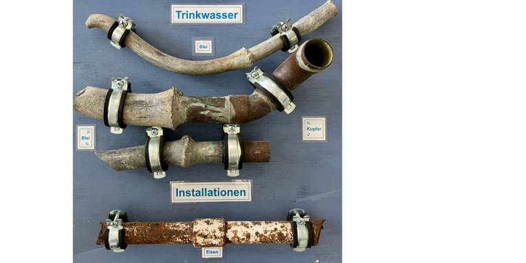 Diverse Rohrabschnitte mit Bleirohren auf einer Schautafel