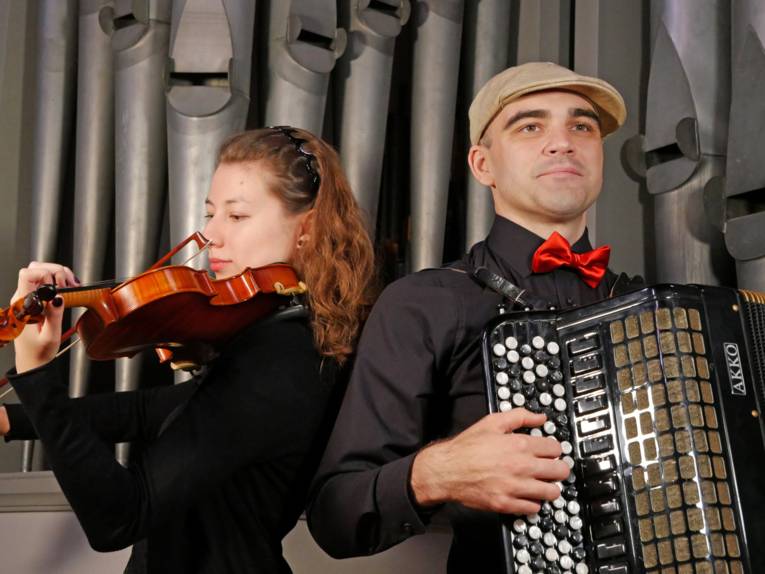 Eine Musikerin spielt auf einer Geige und ein Mann auf einem Akkordeon
