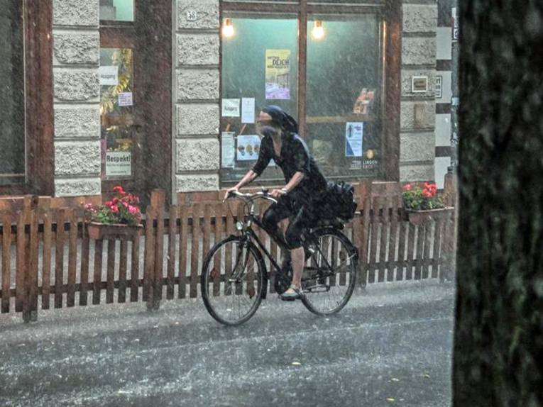 Frau fährt mit Fahrrad durch starken Regen.