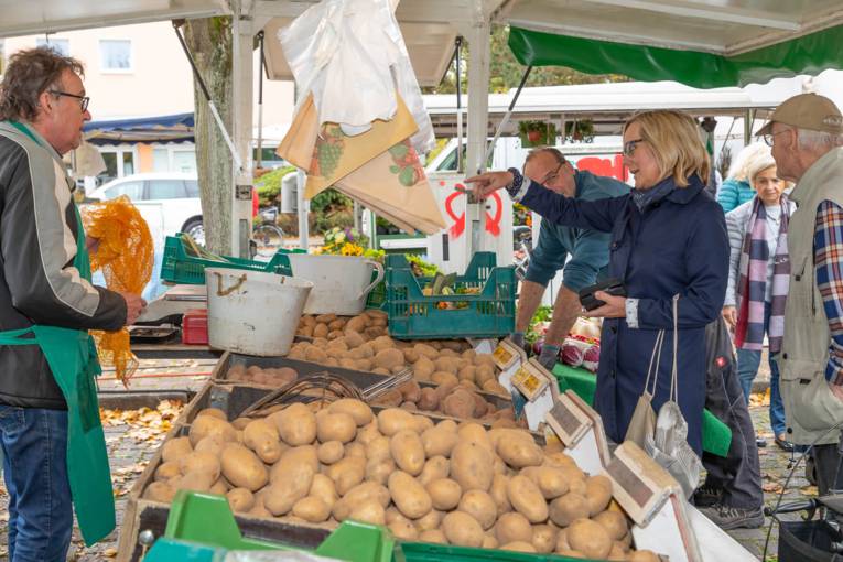 Kundin und Händler im Gespräch am Wochenmarktstand mit den Kartoffeln.
