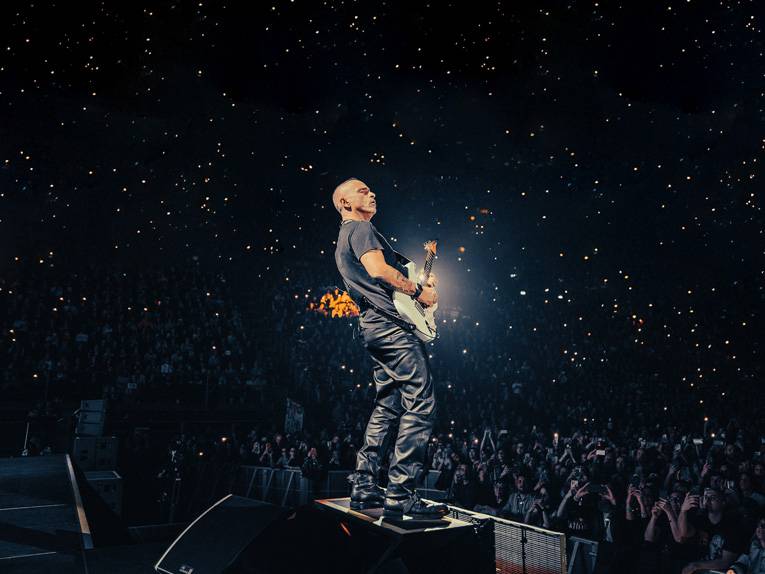 Der italienische Sänger Eros Ramazzotti mit Gitarre auf einer Bühne vor Publikum